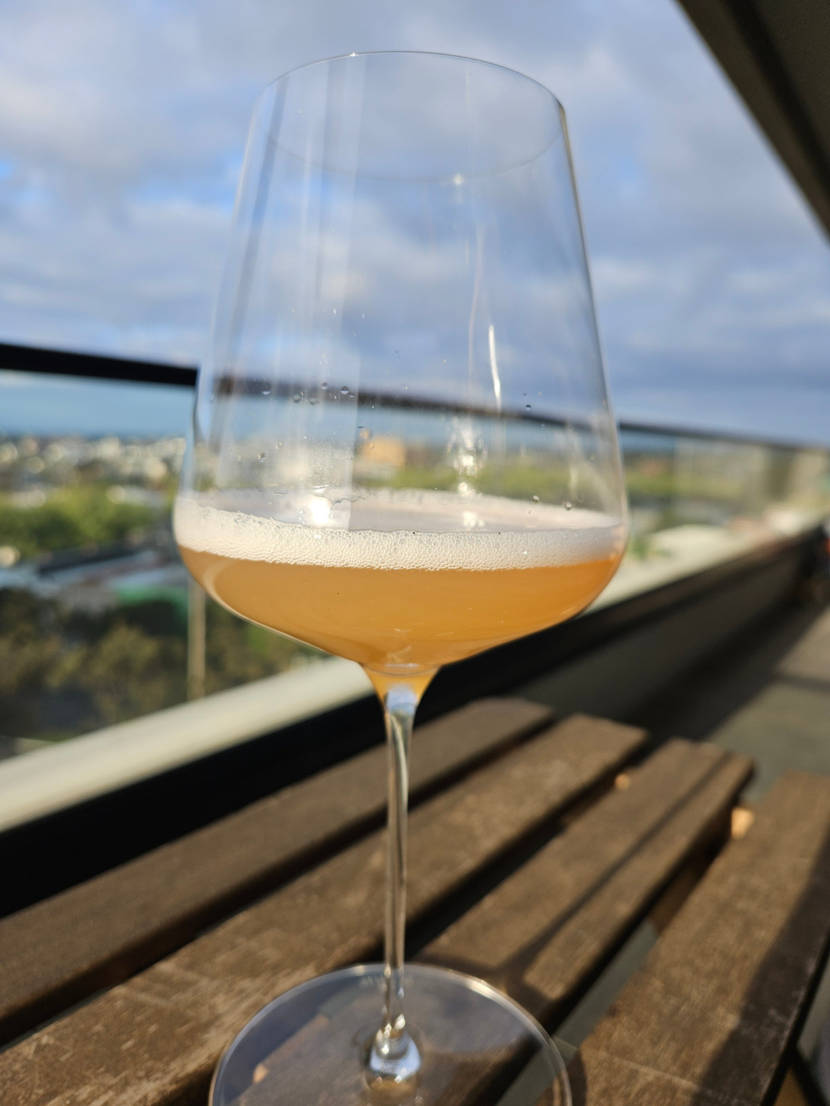 A pale golden Better Brew drink in a stemmed glass beside a sunny window.